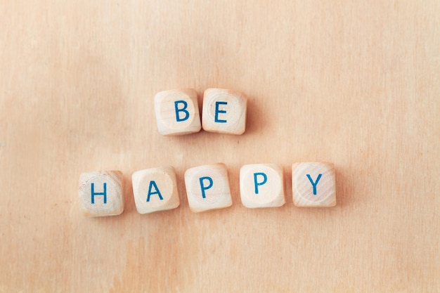 Photo be happy short phrase made with wooden letter blocks on a wooden background