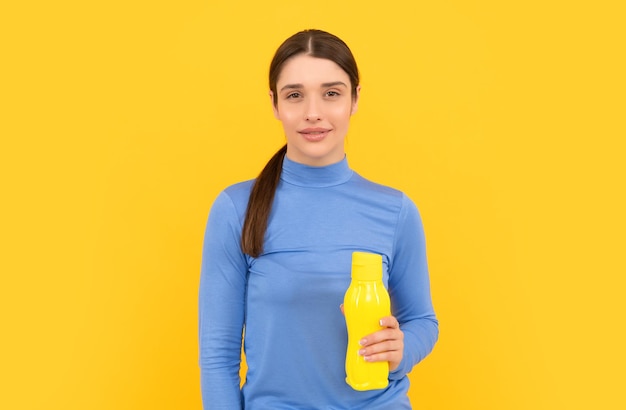 Будьте увлажнены, улыбающаяся женщина держит минеральную воду, чувствует жажду, молодая девушка со спортивной пластиковой бутылкой