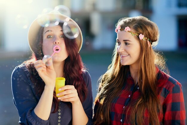 Photo be less serious and more silly instead shot of two young friends blowing bubbles outside