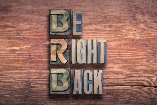 Be right back abbreviation combined on vintage varnished wooden surface