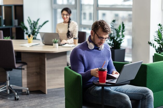 Be serious. Attentive bearded male person bowing head while reading news online