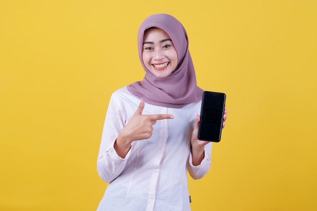 Sii intelligente compra questo dispositivo, ritratto di giovane donna asiatica che ride ad alta voce, indossa l'hijab che punta allo smartphone, mostra lo schermo del dispositivo