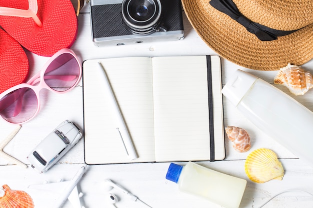 Accessori da spiaggia. borsa, asciugamano, occhiali da sole e flip-flop su fondo in legno. vista superiore con spazio di copia