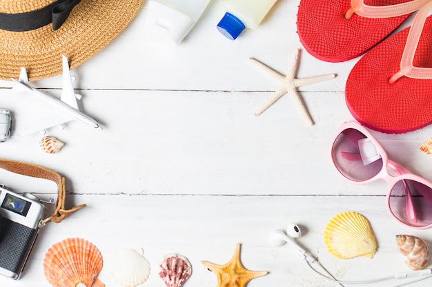 Beach accessories. Bag, towel, sunglasses and flip-flops on wooden background. Top view with copy space