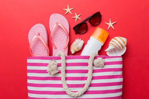 Beach accessories flat lay top view on colored background Summer travel concept Bag with starfish and sea shell Top view