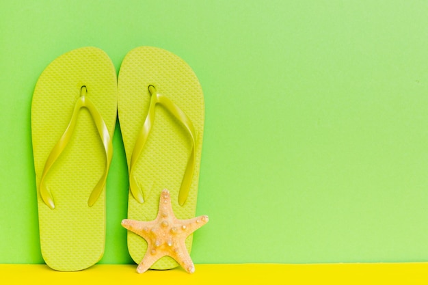 Beach accessories Flip flops and starfish on colored background Mock up with copy space