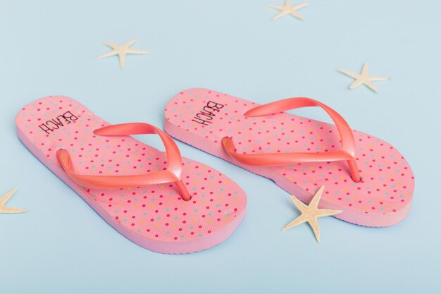 Beach accessories flip flops and starfish on colored background top view mock up with copy space