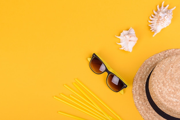 Beach accessories: glasses and hat with shells and sea stars on a colored background. Summer background