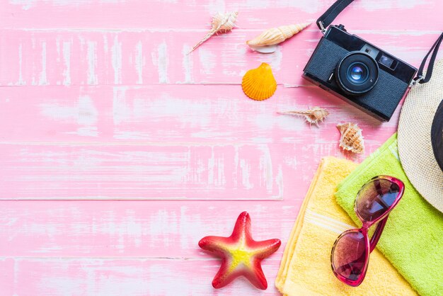 Photo beach accessories on pink pastel wooden background for summer concept.