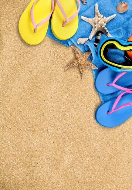 Beach accessories on sand. Flip flops, scuba mask, sea stars, towel