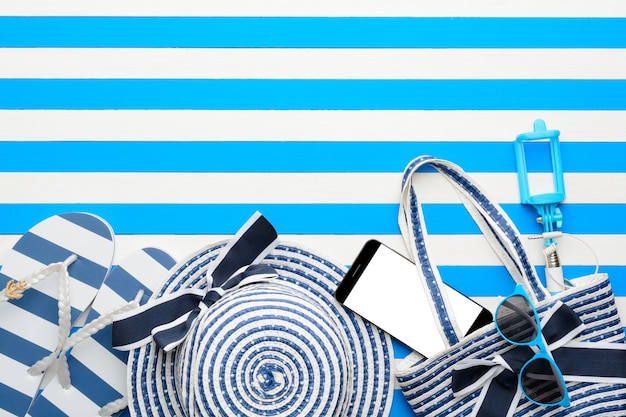 Beach accessories and smartphone on white and blue background. Top view, flat lay.