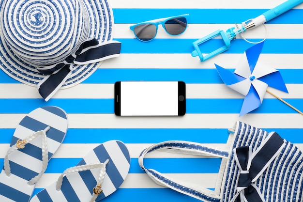 Beach accessories and smartphone on white and blue background. Top view, flat lay.