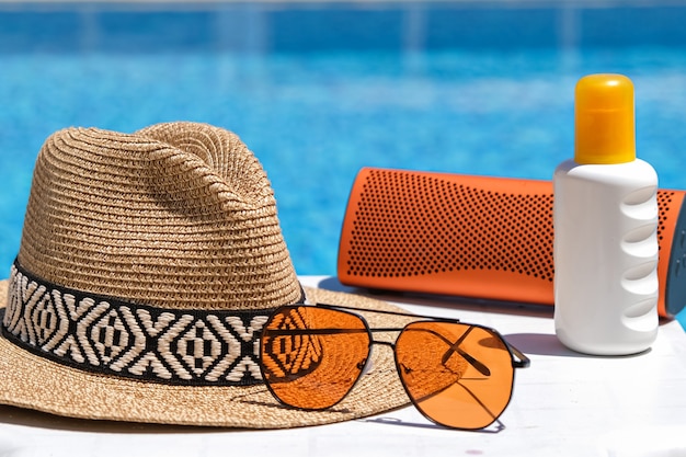 beach accessories swimming pool. Sun cream, sunglasses, music speaker and straw hat