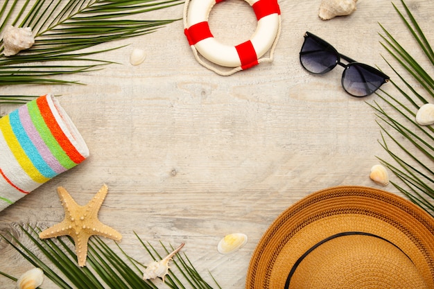 Beach accessories with palm leaves on light background