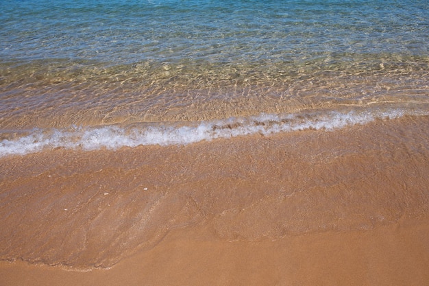 ビーチの背景は熱帯の海のビーチから砂浜の海の景色の美しい海の波を穏やかにします