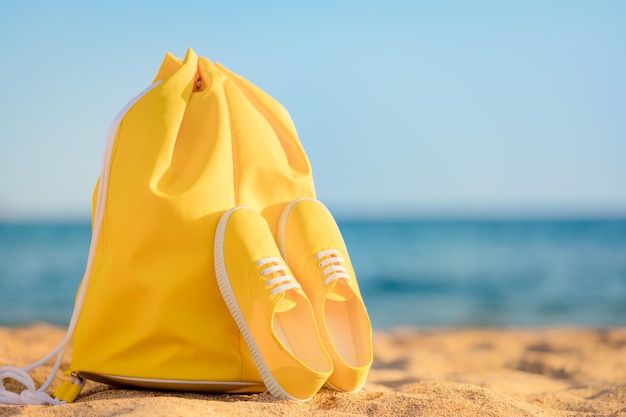 Beach bag and sneakers against blue sea and sky background Summer vacation concept