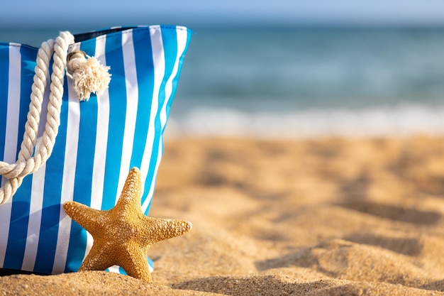 Beach bag and starfish against blue sea and sky background Summer vacation concept