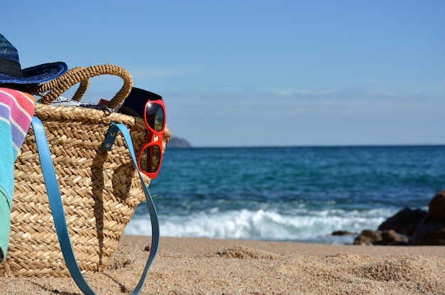 Beach bag with a book and a telephone and sunglasses accompanied by a sea star