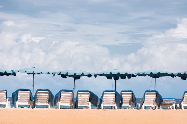 Photo beach blue chair, umbrella on the beach and the bright green sea, on a good day.