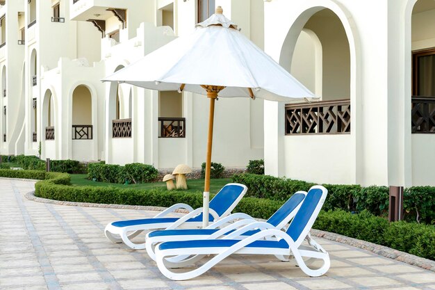 Sedia a sdraio chaise longue vicino alla piscina nel cortile del resort dell'hotel in una calda giornata di sole all'aperto concetto di vacanza ricreativa tropicale estiva