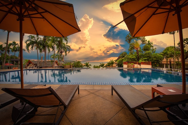 Beach chairs near swimming pool at sunset