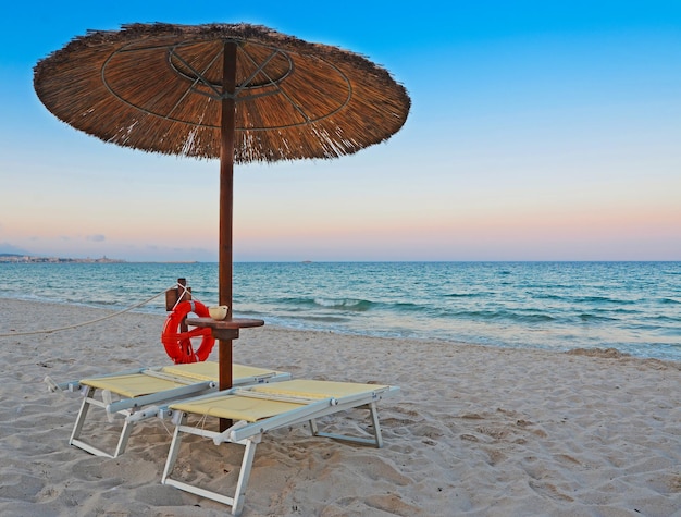 Beach chairs and parasol in Alghero at dawn