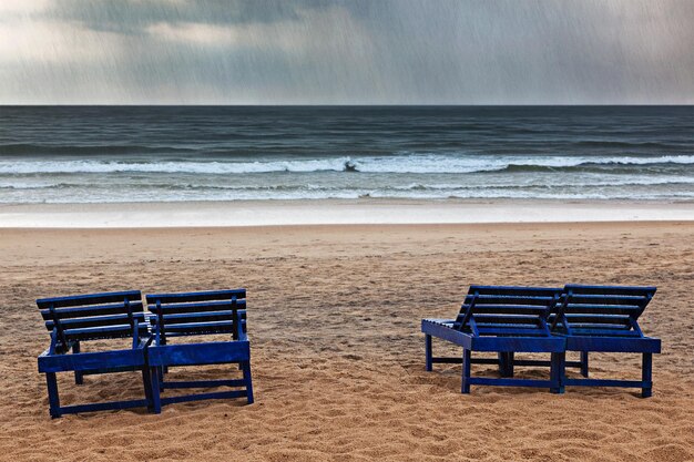 Beach chairs under rain and stormy sea