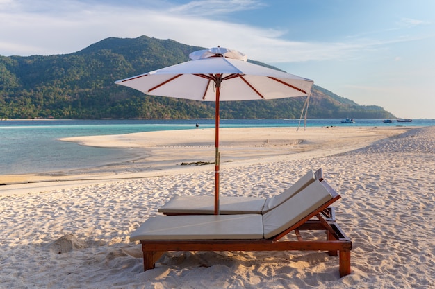 Sedie a sdraio, ombrellone e palme sulla bellissima spiaggia per vacanze e relax all'isola di koh lipe, thailandia