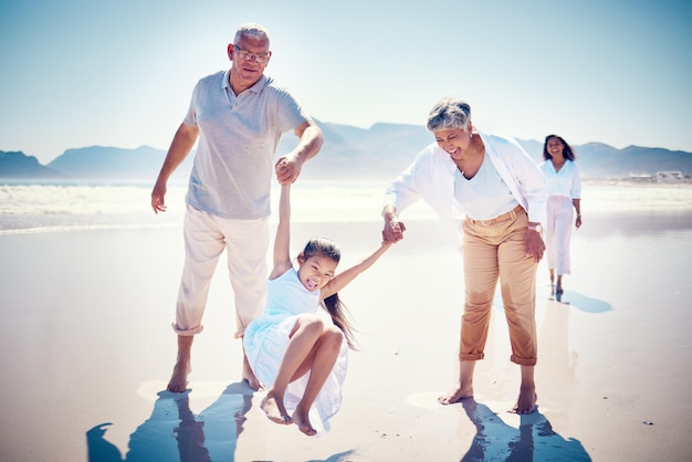 Пляжная семья, держащаяся за руки, бабушка и дедушка с ребенком, играющим и прогуливающимся по песку океана вместе Веселые каникулы и счастливые пожилые мужчина и женщина с детьми, проводящие качественное время и лето на природе
