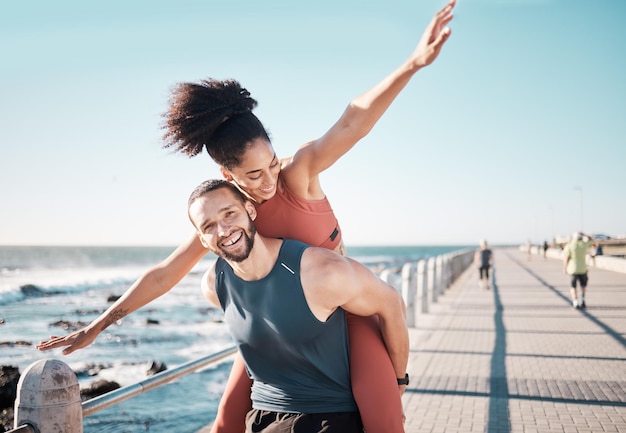 Photo beach fitness and couple piggyback in summer enjoying holiday vacation and quality time on weekend love dating and black man and woman relax after running exercise workout and training by ocean