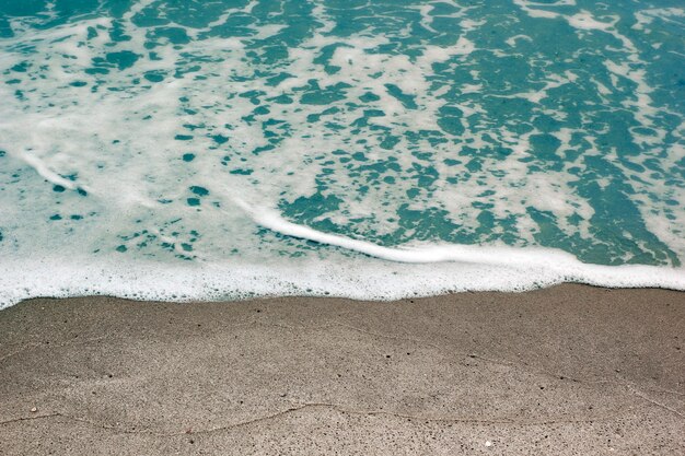 ビーチと海の泡立つ波はぼやけています。