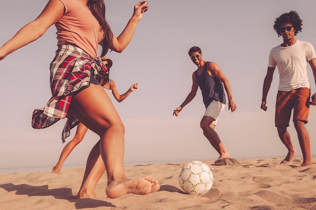 Beach fun. Group of cheerful young people playing with soccer ball on the beach