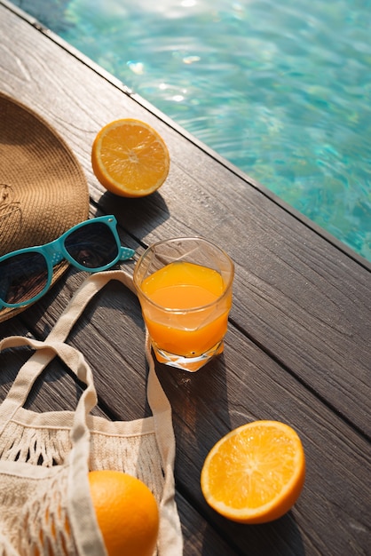 Фото Пляжная шляпа, апельсиновый сок и солнцезащитные очки возле бассейна