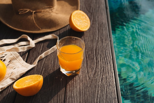 Photo beach hat, orange juice and sunglasses near the swimming pool