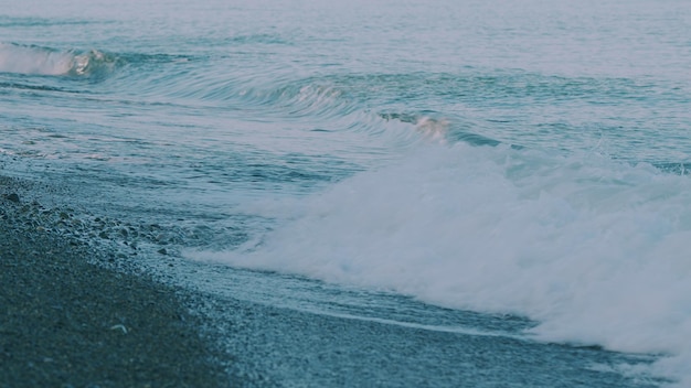 ビーチは小石で覆われていて小さな海の波がビーチに衝突しています
