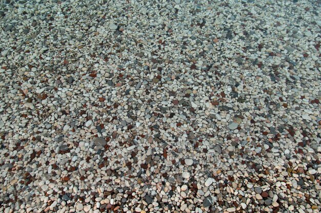 The beach is made of pebbles, the seashore, small colored pebbles in the water. Background, copy space.