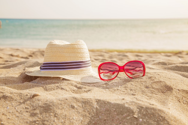 Articoli spiaggia sulla sabbia: occhiali da sole, cappello. viaggio al mare