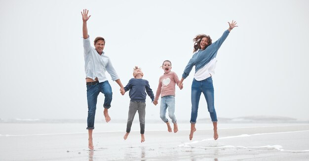 Пляжный прыжок и портрет родителей с детьми, веселящихся на семейном отдыхе и отдыхе на выходных Счастье в маме, папе и детях, прыгающих у океана, наслаждающихся природой на открытом воздухе и морем