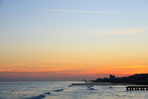 Пляжный пейзаж на рассвете. Перспективный вид пирсов с людьми. Вид на пляж Езоло, итальянская панорама