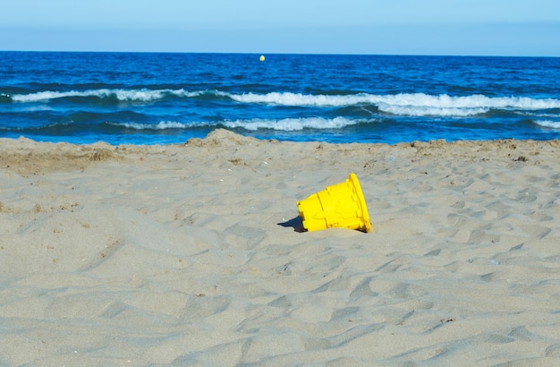 beach landscape with waves and yellow bucket