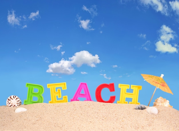 Foto lettere da spiaggia su una spiaggia di sabbia contro il cielo blu