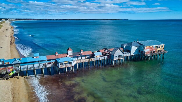 Beach on maine ocean aerial over large wood pier covered in shops