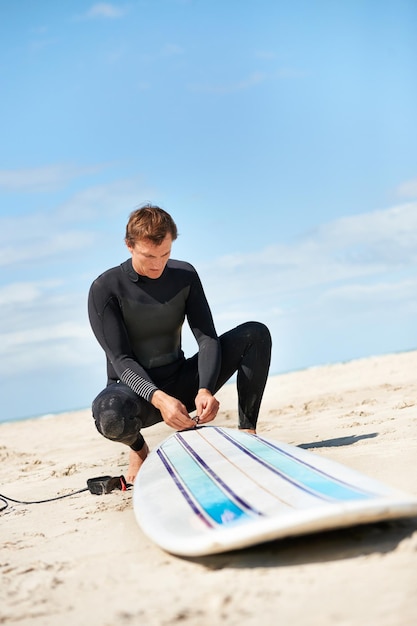 beach man and surfboard rope outdoor in summer for exercise fitness and workout surfer wetsuit and person with leash by ocean for safety preparation water sports and travel on holiday by sea