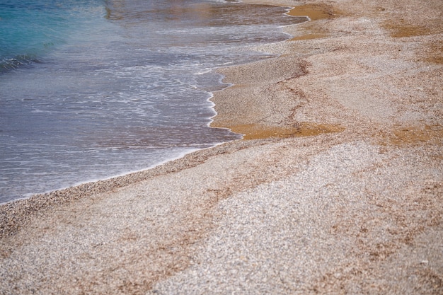La spiaggia della costa mediterranea con onde di acqua azzurra. brezza marina estiva. mare con tempo soleggiato