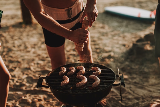 Beach Party Concept. Man Grills Barbecue Sausages.