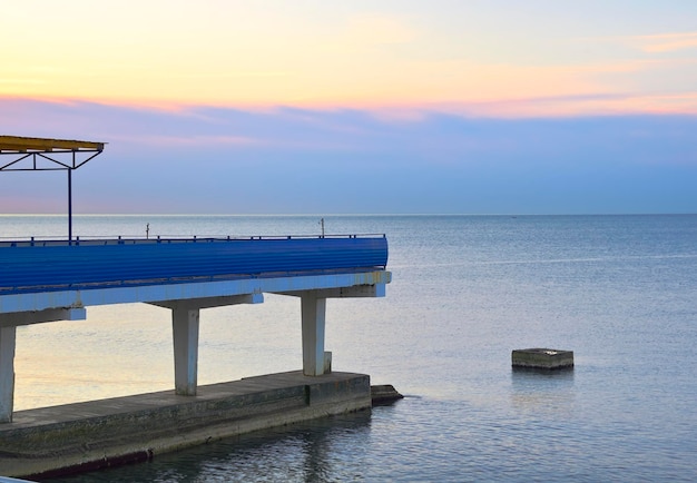 A beach pier above the water against a bluepink sky Sochi Russia 2021