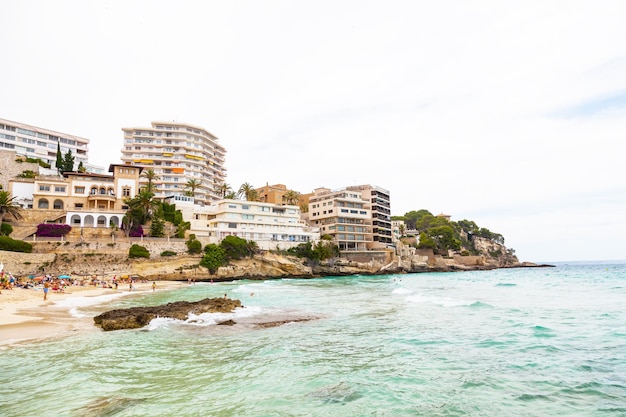 Beach among the rocks on Palma de Mallorca Sea people hotels and residential buildings