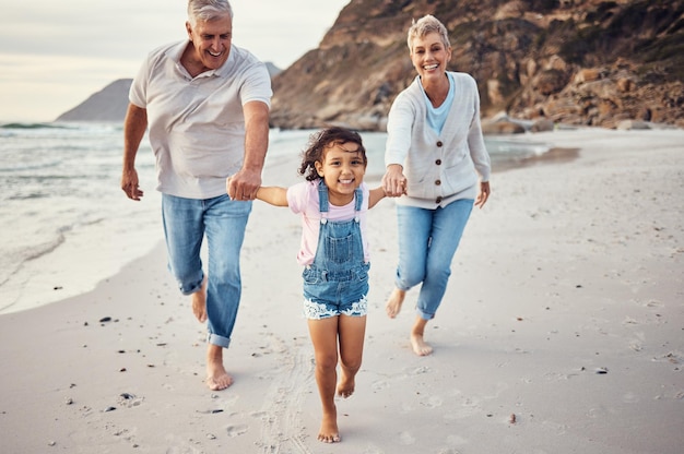 휴일 휴가에 사랑스러운 결합 경험을 위해 조부모와 손을 잡고 있는 해변 달리기와 아이 행복한 할머니와 노인은 가족으로서 아이와 함께 운동을 즐기는 것을 즐깁니다