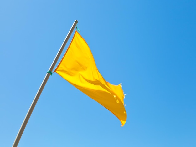 Beach safety warning yellow flag with blue sky