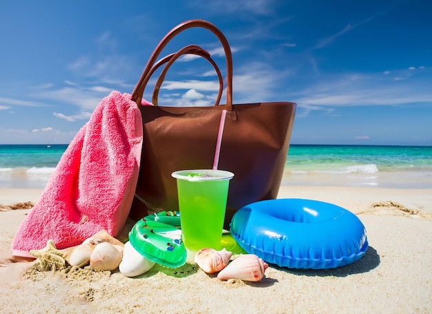 A beach scene with a beach towel and a beach bag with a drink and a beach towel.